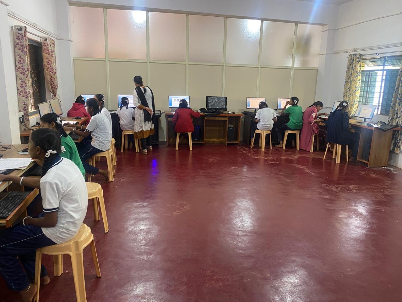 Schoolgirls at desktop computers with an instructor